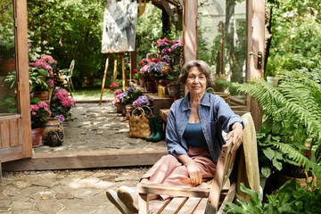 Charming senior woman relaxing in a blooming garden surrounded by vibrant flowers