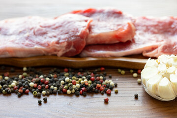 Close-up of beef tenderloin on a wooden board with spices and peppers