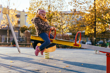 Autumn playground moment with girl with Down syndrome on seesaw