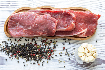 Close-up of beef tenderloin on a wooden board with spices and peppers