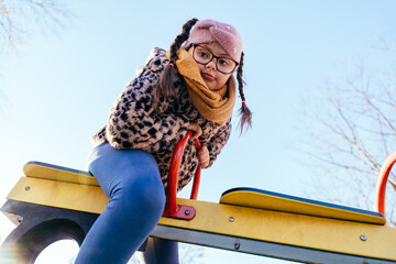 Thoughtful girl with Down syndrome sitting high on seesaw