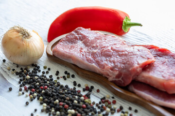 Close-up of beef tenderloin on a wooden board with spices and peppers