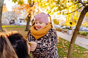 Funny girl with Down syndrome playing with autumn leaf