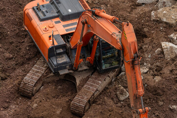 A large orange excavator is sitting in a muddy field. The mud is deep and the machine is covered in...