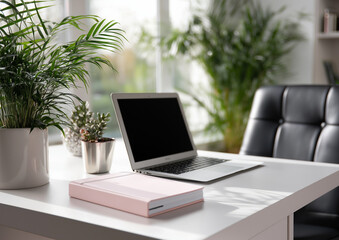A photo of a white desk with a pink notebook, laptop, and glasses on it