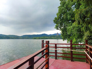 The beautiful view of the West Lake (Xi Hu) with red wood fence floor and Leifeng Pagoda background.