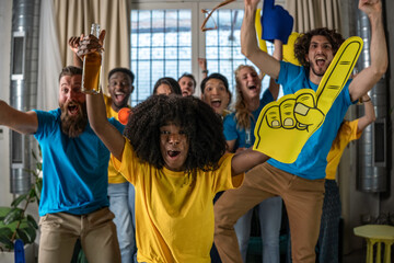 Diverse group of young fans celebrating a thrilling match win at home, with foam fingers, drinks, and pure energy. Joyful reactions and colorful expressions fill the room. Team spirit concept.
