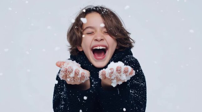 Joyful child in dark sweater smiling and playing with falling snowflakes on a bright winter day