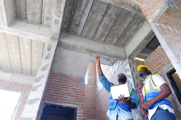 The engineer reviews the house structure plans and walks around the construction site — concept...