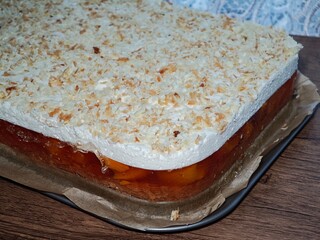 A tray with a rectangular, no-bake cake for hot weather, with white cream and orange jelly with peaches