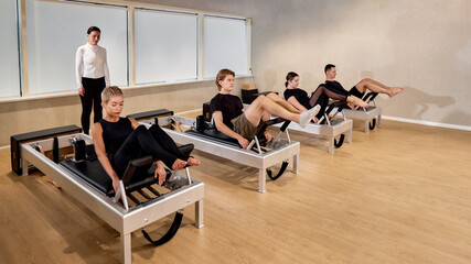 Group fitness class practicing Pilates on reformer machines with instructor guidance
