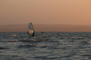 windsurfer at sunset on a wavy lake