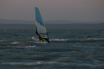 windsurfer on stormy lake after sunset