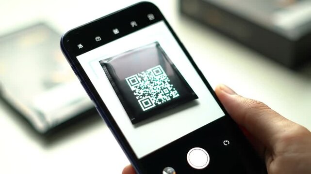 Person holding smartphone and scanning QR code on packaging  