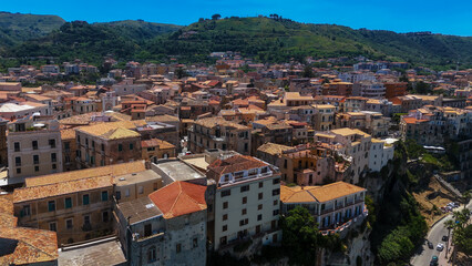 Fototapeta premium Aerial view of Tropea, a charming town perched on a cliff overlooking the Tyrrhenian Sea, showcasing its terracotta rooftops and the beautiful Calabrian landscape
