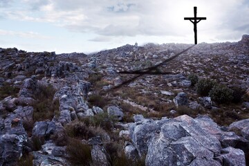 Rugged rocky hillside is showing in flat design with solitary cross casting shadow under cloudy sky