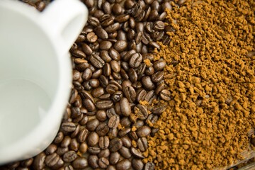 Flat design is showing overhead white ceramic coffee mug atop roasted beans blending into granules © vectorfusionart