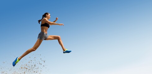 Low angle view of female athlete long jumping
