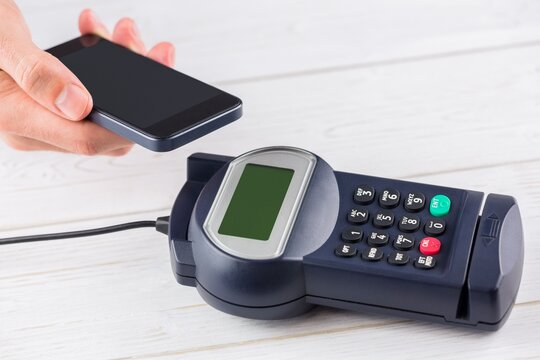 Contactless payment processing with smartphone and POS terminal in flat design on wooden countertop - Powered by Adobe