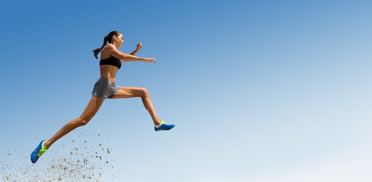 Low angle view of female athlete long jumping
