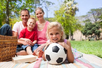 Little blond girl holding a soccer ball at a picnic