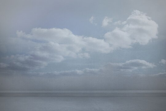 Fototapeta Ocean water is gently rippling across horizon line under soft cumulus clouds in flat design