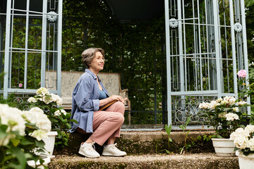 Senior woman enjoys tranquility in a blooming garden, surrounded by vibrant flowers