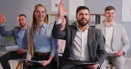 Interested engaged smiling audience asking questions at conference. Group of young people, entrepreneurs and colleagues, attending business event and listening to entrepreneurship or marketing lecture