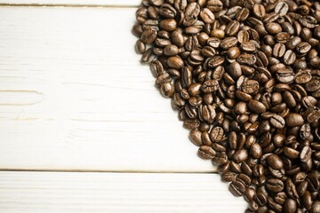 Mound of roasted coffee beans is being shown in flat design on white-painted wood plank surface