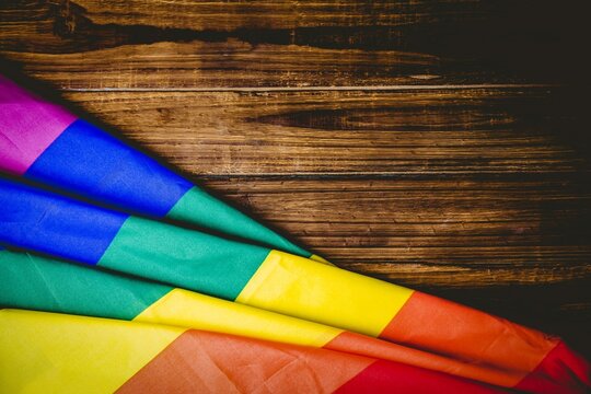Fototapeta Flat design draping folded rainbow-striped flag on wood planks creating vivid contrast, copy space