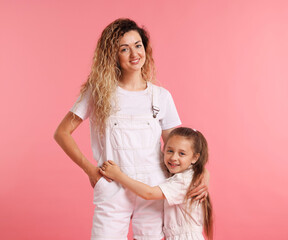 Family portrait of happy mother and her daughter on pink background