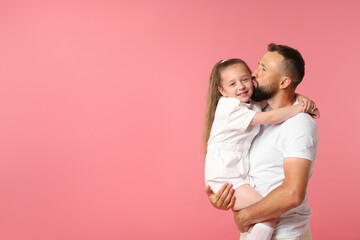 Family. Father kissing his happy daughter on pink background. Space for text