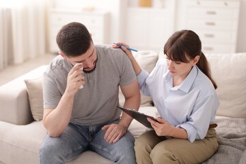 Psychologist supporting patient during therapy session on sofa in office