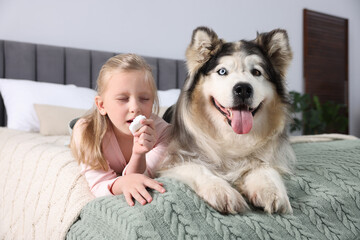 Girl suffering from allergy with her dog on bed at home