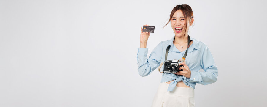 Travel girl smiling with credit card bank and photo camera for travel. Excited Asian young woman enjoys shopping and photography on vacation trip financial. isolated studio white background - Powered by Adobe