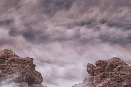 Fototapeta Flat design showing two red-brown sandstone formations rising under gray storm clouds