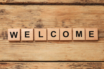 Word Welcome made of wooden cubes on table, top view