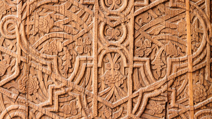 Traditional wood carving with oriental floral and geometric patterns, close-up of wood panel texture. Ancient handcrafted arts and crafts concept