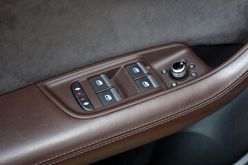 Close-up of the car window regulator buttons in a brown leather car interior. Window control...
