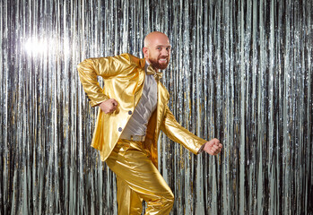 Funny man dancer in golden suit enjoys dancing to disco music during evening party, filled with fun...