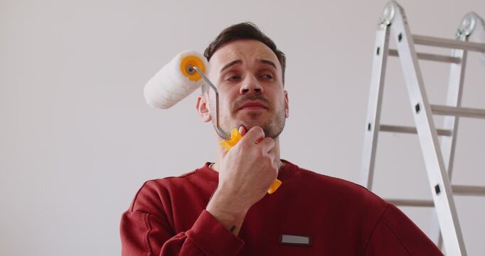 Pensive worried painter, construction worker troubled with painting wall expanses, holding paint roller brush, service man failed finishing task for room, building repair, thinking of new interior 