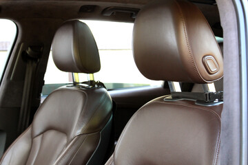 Modern luxury car brown leather interior. Part of orange leather car seat details with white...