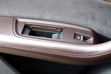 Ashtray on rear passenger door of luxury SUV in open position. Brown leather door trim with gray...