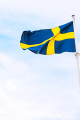 The national flag of Sweden waving on a pole against a clear blue sky.