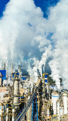 Fumaça branca sai de grandes chaminés de uma indústria de papel e celulose, evidenciando a intensa produção e impacto ambiental visível na paisagem