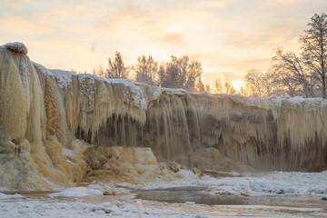 Beautiful frozen Jagala waterfall (Estonian - Jägala) on a sunny winter morning. Cascading icicles. Beautiful sky in the background.
