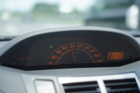 車のダッシュボードに設置されたスピードメーターが鮮やかなオレンジ色の照明で照らされており針が静止状態を示している現代的な自動車の計器盤の詳細な写真で運転席からの視点で撮影されたドライブや交通をテーマにした画像