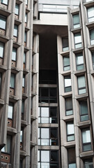 Tall grey concrete apartment building with repetitive windows in urban setting