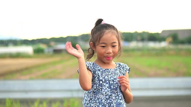A little Asian girl waving her hands, saying bye-bye or goodbye