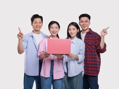Enthusiastic group of young adults presenting a new laptop pointing upwards and expressing joy - Powered by Adobe